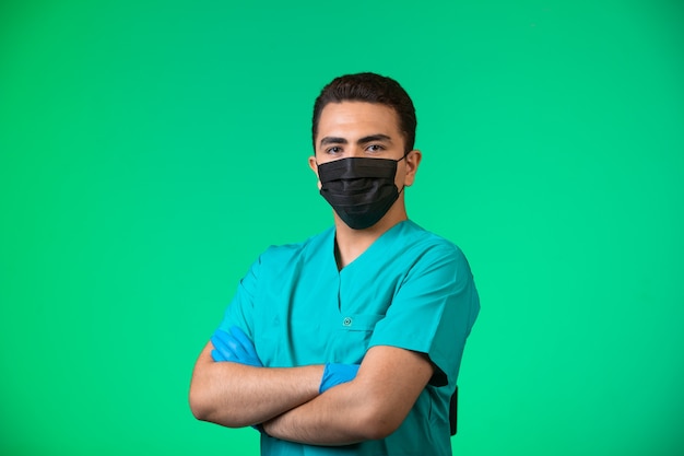 Foto gratuita doctor en uniforme verde y mascarilla haciendo posando en posición satisfecha.