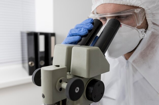 Doctor usando un microscopio para comprobar la muestra de covid