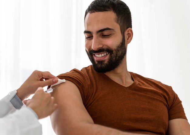 Doctor vacunando a un apuesto hombre sonriente