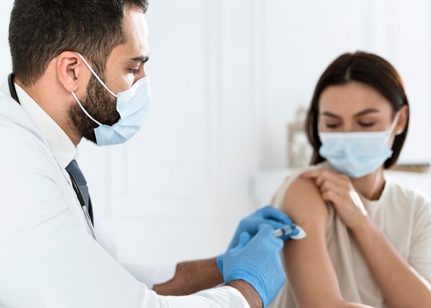 Doctor vacunando a una mujer joven