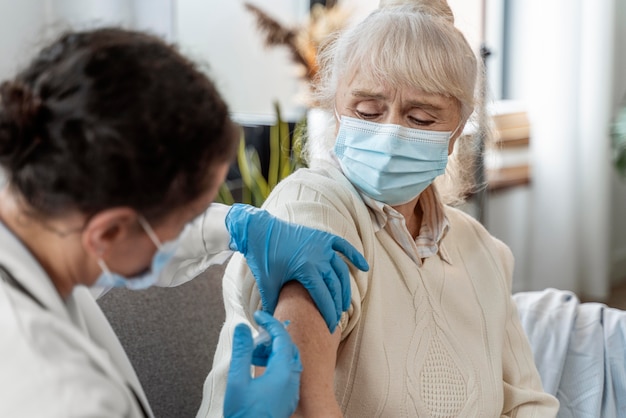 Doctor vacunando a una mujer mayor