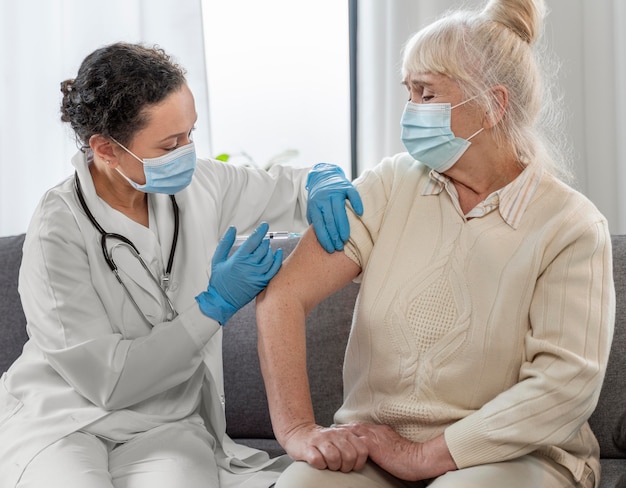 Doctor vacunando a una mujer mayor