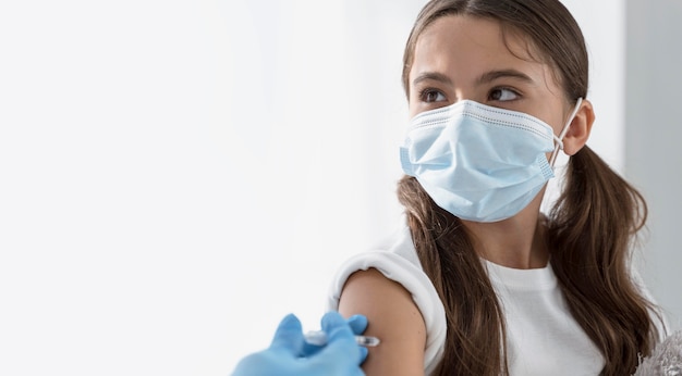 Doctor vacunando a una niña con espacio de copia