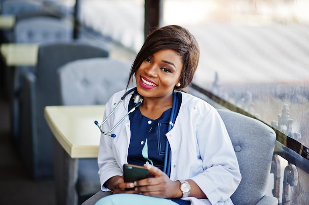 Una doctora afroamericana con estetoscopio miró el teléfono y se sentó en la clínica