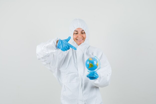 Doctora apuntando al globo terráqueo en traje protector