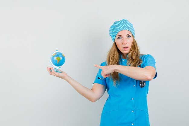 Doctora apuntando al mundo en uniforme azul