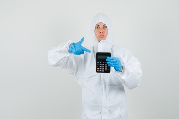 Doctora apuntando a la calculadora en traje protector