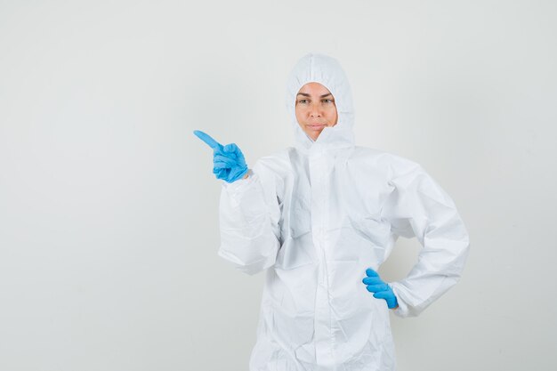 Doctora apuntando hacia fuera en traje protector