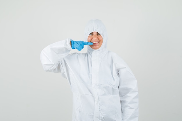 Doctora apuntando a sus dientes en traje protector