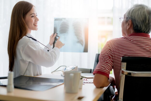 Una doctora asiática consulta y examina el resultado de la radiografía con un paciente mayor con cuidado y enfoque