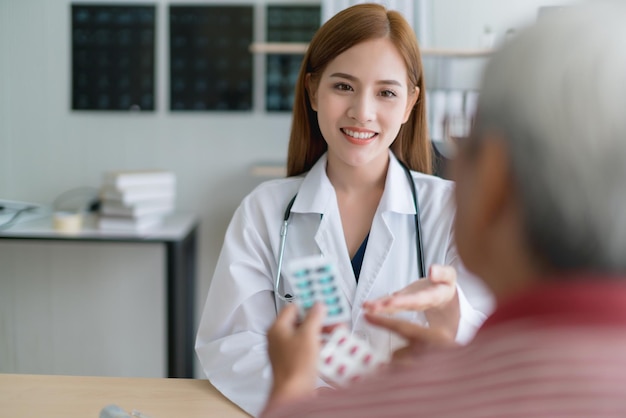 Una doctora asiática inteligente y atractiva explica y discute con un anciano asiático para consultar el concepto de salud de fondo de la clínica