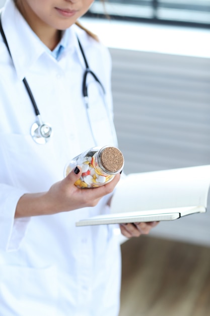 Foto gratuita doctora asiática, mujer especialista con cuaderno y pastillas