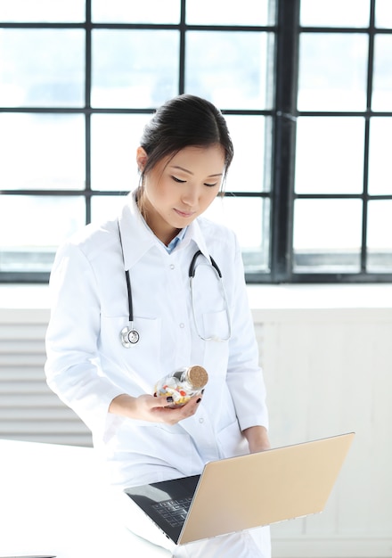 Doctora asiática, mujer especialista con laptop y pastillas