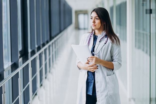 Doctora atractiva de pie con documentos en el hospital