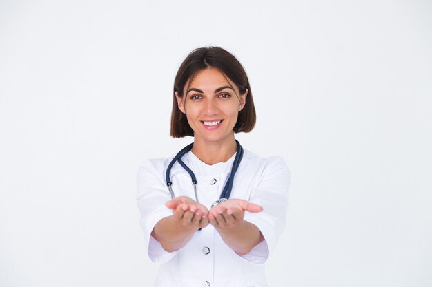 Doctora en bata de laboratorio en blanco aislado, sonrisa confiada tomar de la mano con espacio vacío