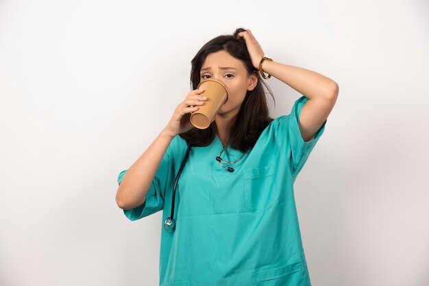 Doctora bebiendo una taza de café sobre fondo blanco. Foto de alta calidad