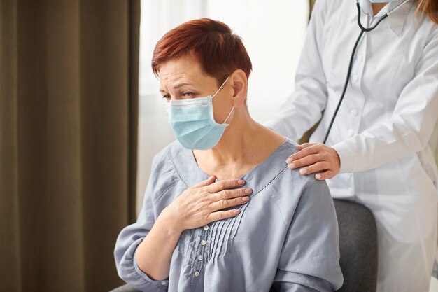 Doctora del centro de recuperación de Covid que controla al paciente mayor con máscara médica