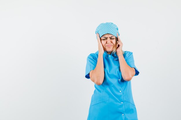Foto gratuita doctora cogidos de la mano a la cabeza en uniforme azul y con aspecto enfermo