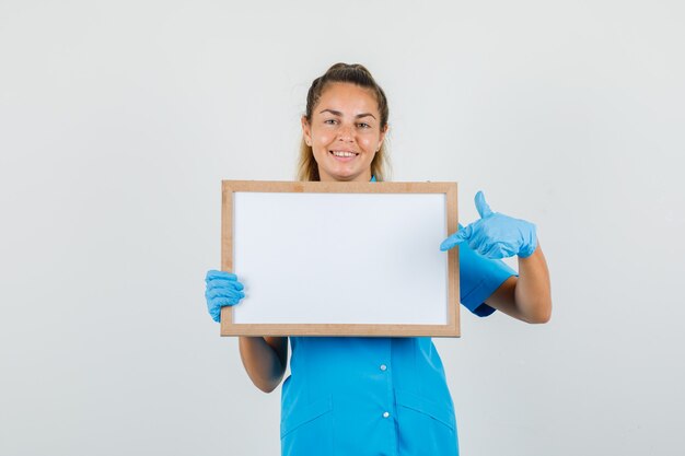 Doctora con el dedo acusador en la pizarra en uniforme azul