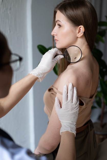 Doctora diagnosticando un melanoma en el cuerpo de una paciente