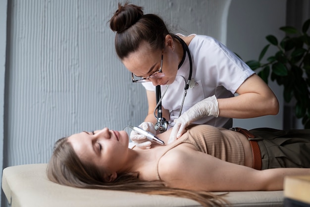 Doctora diagnosticando un melanoma en el cuerpo de una paciente