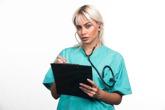 Doctora escribiendo algo en el portapapeles sobre fondo blanco. Foto de alta calidad