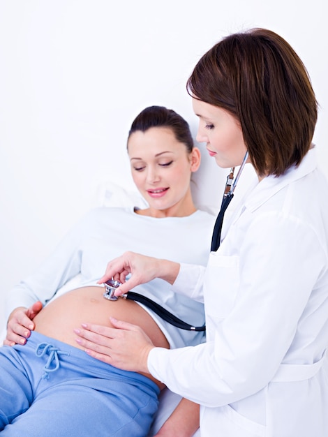 Foto gratuita doctora escucha el estómago de una mujer embarazada
