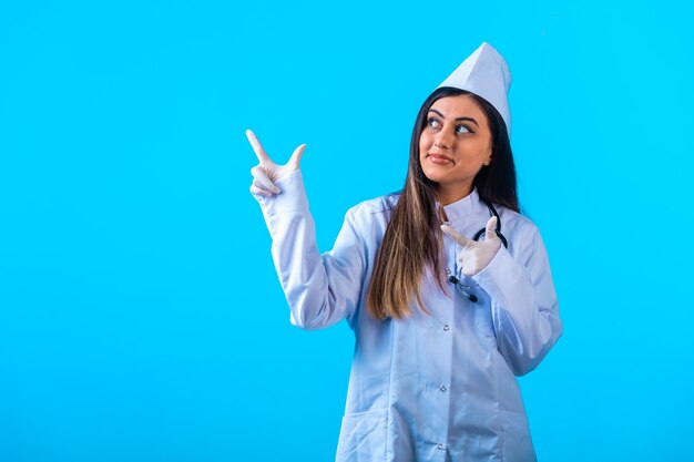 Doctora con estetoscopio apuntando a algo arriba