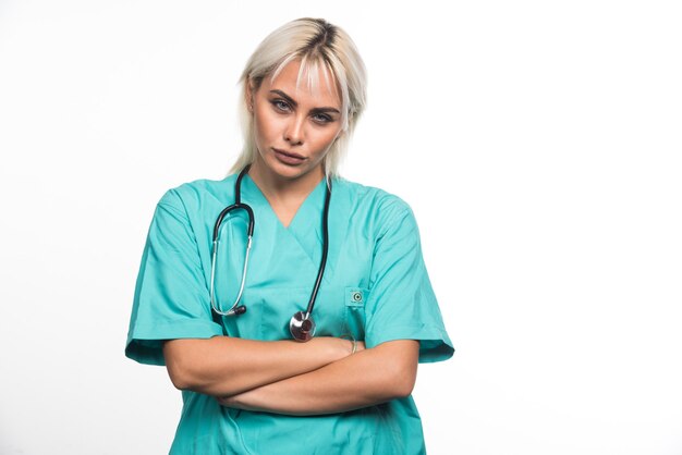 Doctora con estetoscopio cruzando los brazos sobre fondo blanco. Foto de alta calidad