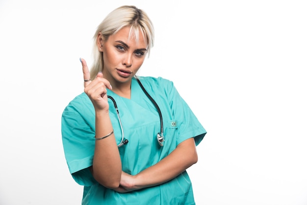 Doctora con estetoscopio dedo acusador sobre fondo blanco. Foto de alta calidad