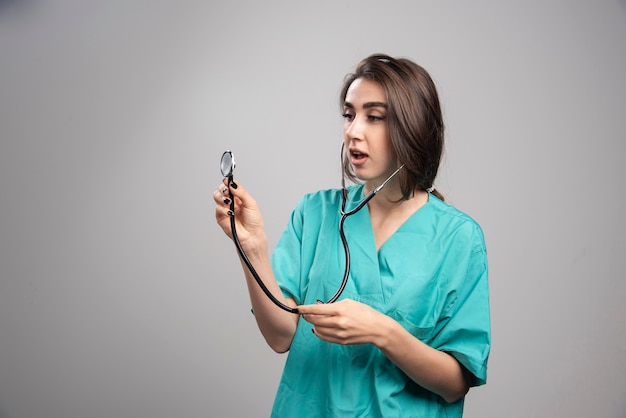 Doctora con estetoscopio posando sobre fondo gris. Foto de alta calidad