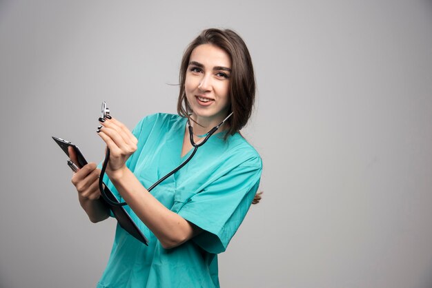 Doctora con estetoscopio sobre fondo gris. Foto de alta calidad