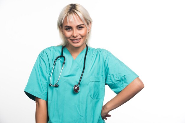 Doctora con estetoscopio sonriendo sobre superficie blanca