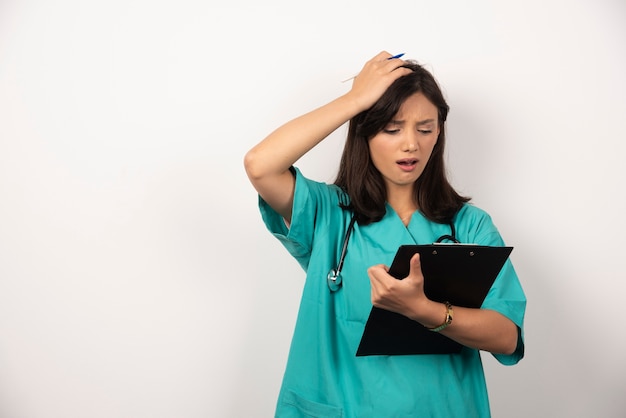 Doctora con estetoscopio sorprendida por los resultados sobre fondo blanco.