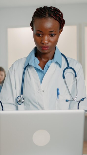 Doctora con estetoscopio trabajando con computadora portátil moderna para curar al paciente en la sala del hospital. Especialista médico que usa un dispositivo para curar los síntomas de la enfermedad y la enfermedad con medicamentos y tratamientos.