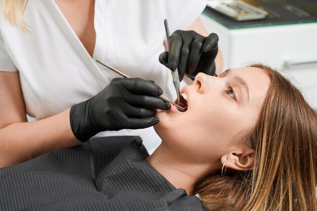 Doctora examinando dientes de pacientes en clínica dental