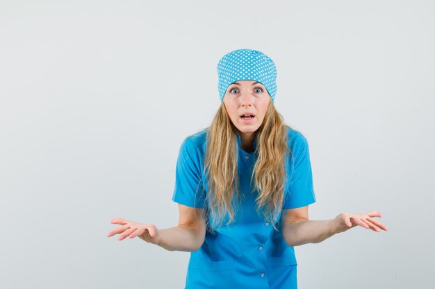 Doctora extendiendo las palmas en gesto de desconcierto en uniforme azul