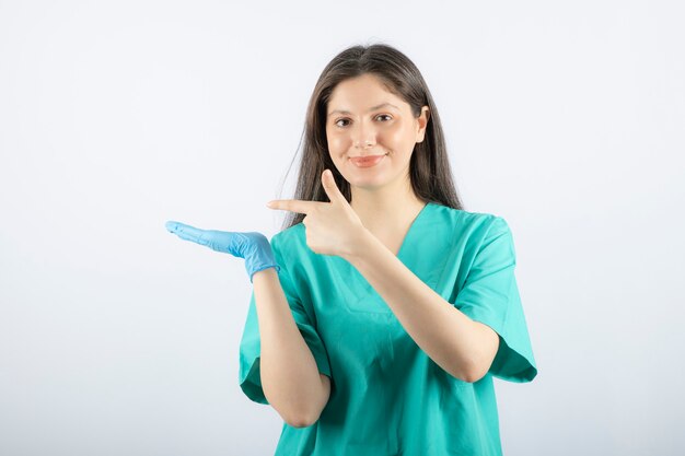 Doctora en guantes médicos mostrando las manos en blanco.