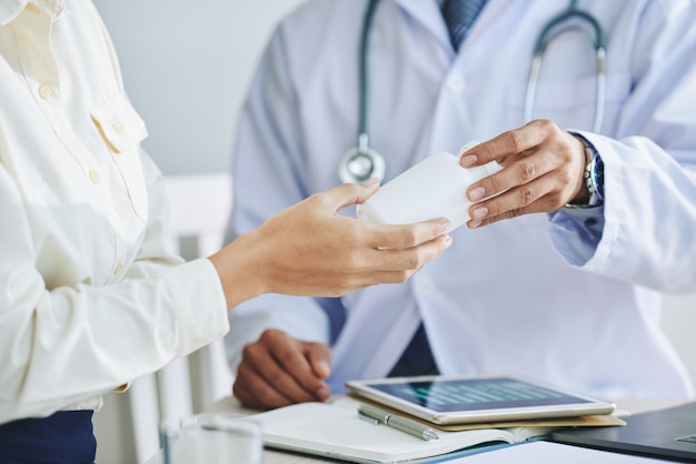 Doctora irreconocible dando medicamentos al paciente