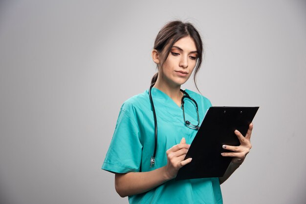 Doctora leyendo notas en gris