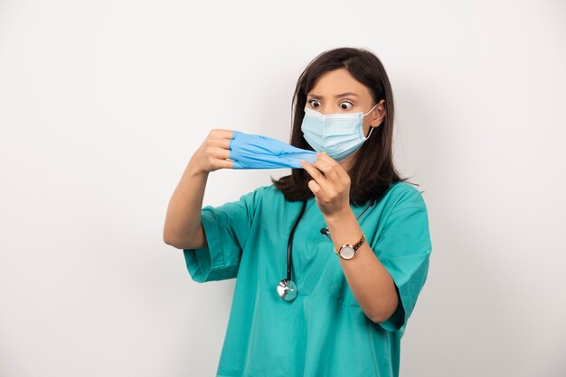 Doctora con máscara médica con guantes sobre fondo blanco. Foto de alta calidad