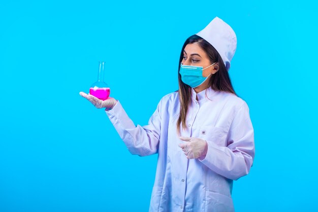 Doctora en máscara sosteniendo un matraz de prueba