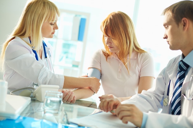 Doctora midiendo la presión arterial del paciente