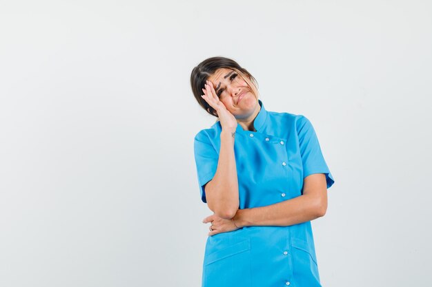 Doctora mirando hacia arriba en uniforme azul y mirando triste