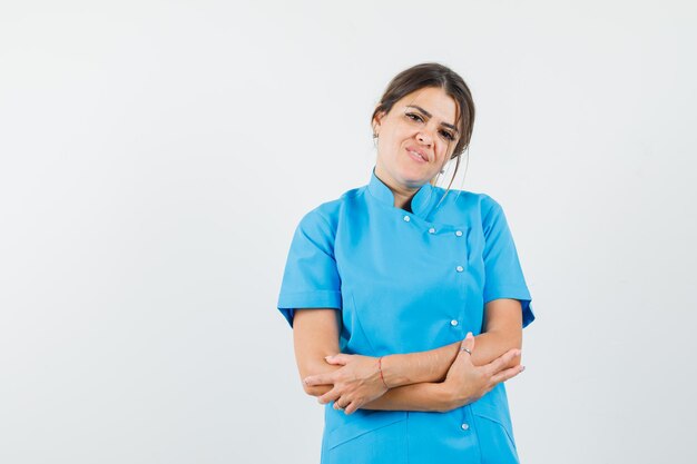 Doctora mirando a la cámara en uniforme azul y mirando esperanzado