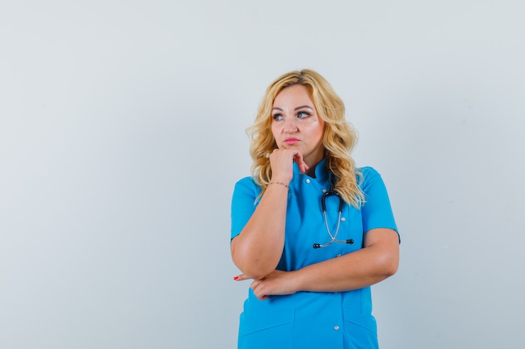 Foto gratuito doctora mirando a otro lado en uniforme azul y mirando pensativo. espacio para texto