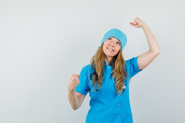 Doctora mostrando gesto ganador en uniforme azul y con suerte