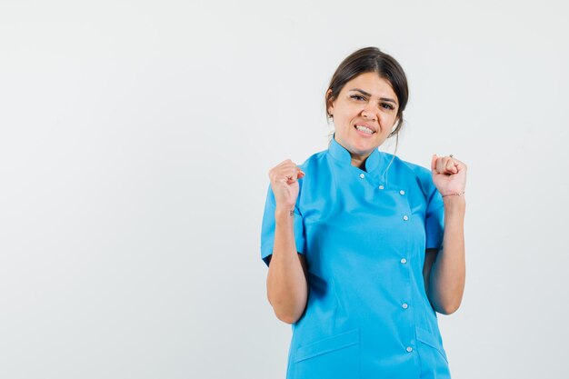 Doctora mostrando gesto ganador en uniforme azul y con suerte