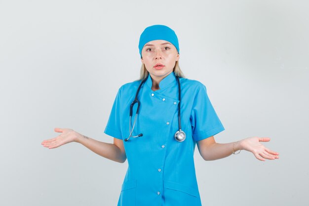 Doctora mostrando gesto de impotencia en uniforme azul y mirando confundido.