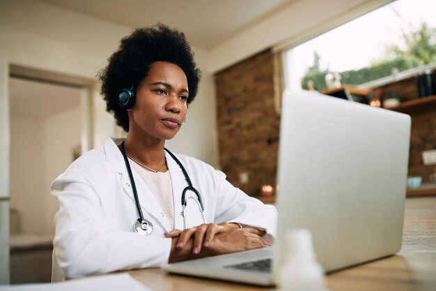 Doctora negra que tiene una llamada de conferencia a través de una computadora portátil